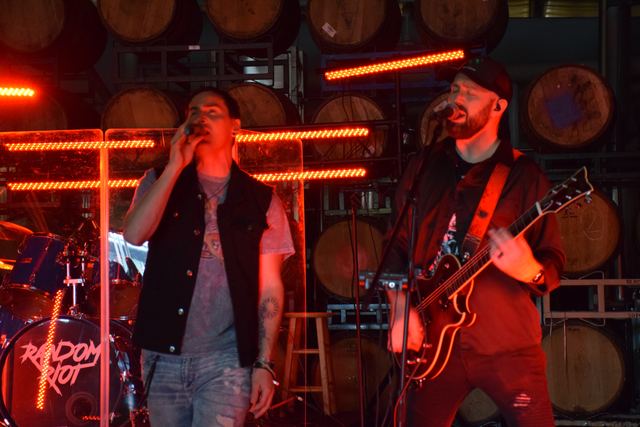 Singer and guitarist side by side under red light