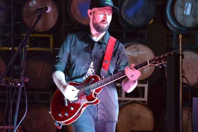 Guitarist with a red hollow-body, singing into the mic