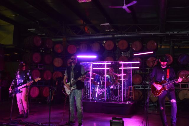 Random Riot playing the full set, all five members spread across the stage under purple lights in a barrel room
