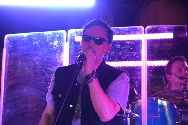 Singer at the mic in sunglasses, purple light behind