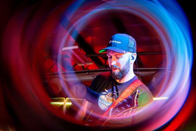 Bass player in a ball cap, framed by red and blue light trails