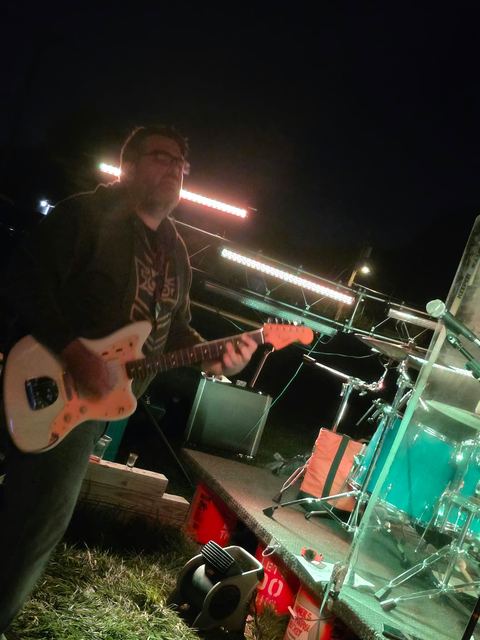 Guitarist playing at the front of the stage under green light