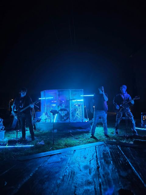 Wide view of the band playing outdoors after dark, blue light across the stage