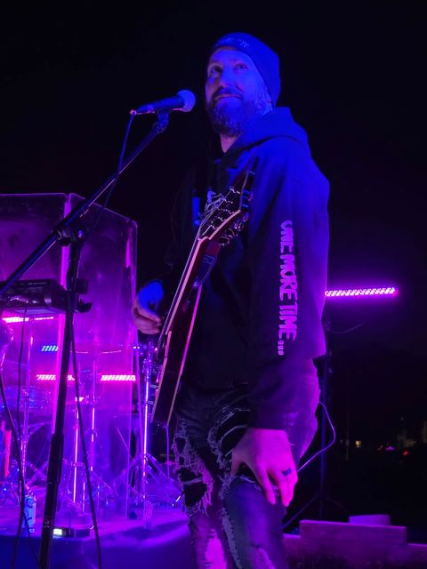 Singer at the mic, blue and magenta light behind