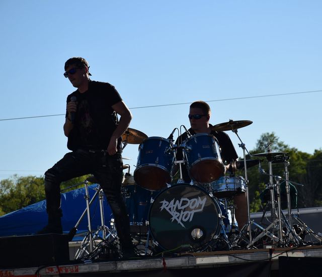 Random Riot playing an outdoor stage in daylight, drum kit front and centre